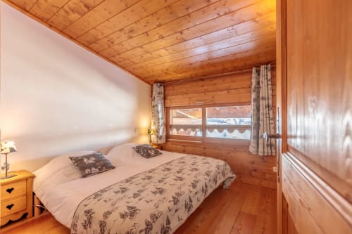 Cozy wooden bedroom with mountain views at Cosyarc, Bourg-Saint-Maurice. Queen bed with ski access overlooking Mont Blanc.