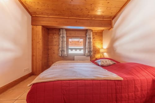 Wooden bedroom of the CosyArc apartment in Arc 1800 with red bedding, ski-in/ski-out with views of Mont Blanc