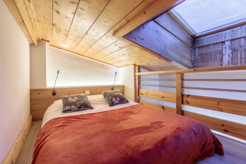 Cosy mezzanine bedroom of the CosyArc apartment in Arc 1800, light wood decor, red bedding, and natural light from the Velux skylight