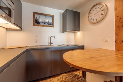 Modern kitchen with dark cabinets and wooden table in the CosyArc Saint-Bernard apartment in Arc 1800,