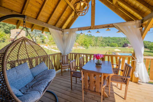 Patio van de Mayreau-kamer in Domaine De Campagnac met eettafel, hangstoel en uitzicht op het platteland