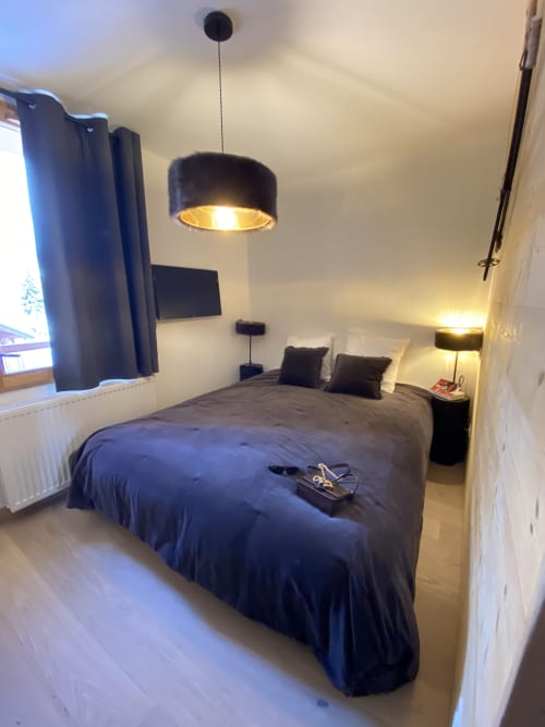 Modern bedroom at Le Champenois apartment in Hermonville with dark bed, pendant lighting, and mountain views through window