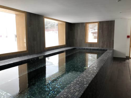 Indoor heated pool with dark tile walls and wooden window frames at Le château d'Hermonville, Hermonville