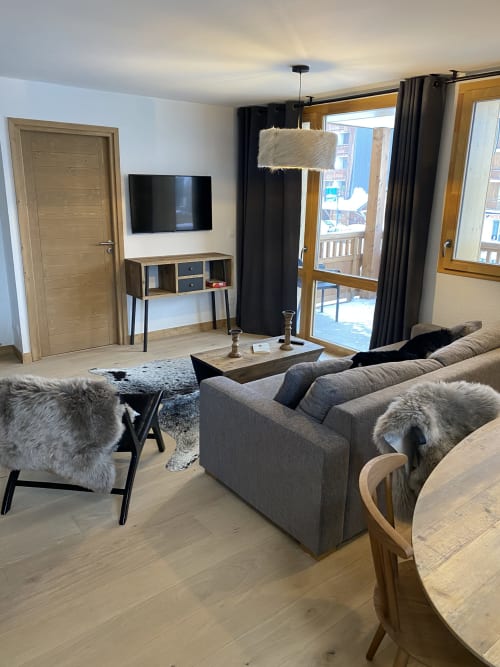 Modern apartment living room at Le Champenois with gray sofa, TV, private terrace, and mountain views in Hermonville