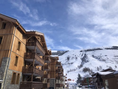 Bâtiments en bois rustiques du château d'Hermonville avec pistes enneigées en arrière-plan