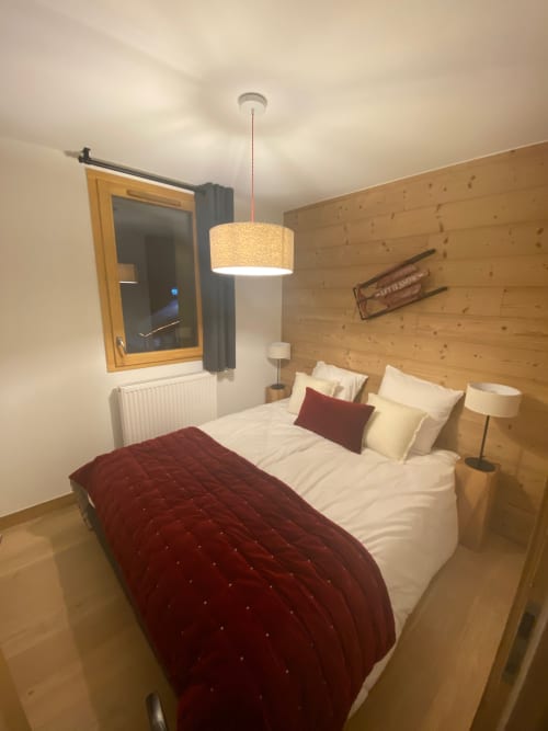Cozy bedroom at Le château d'Hermonville with wood paneling, queen bed, pendant light, and modern amenities in Hermonville