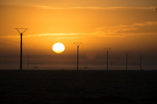 Sunset over Vallières-les-Grandes with silhouetted power lines under golden sky