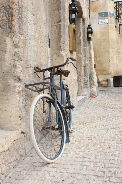 Vintage blue bicycle leaning against stone wall in narrow European alley, Les gîtes des châteaux