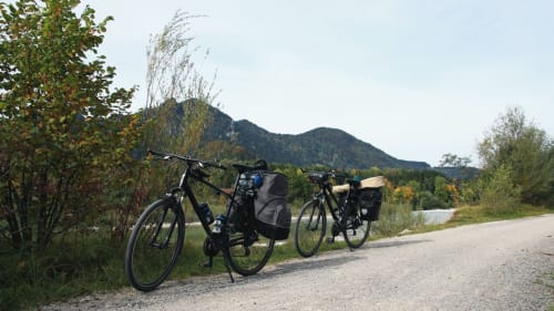 Two bicycles on a gravel path near Vallières-les-Grandes, with mountains and river in background