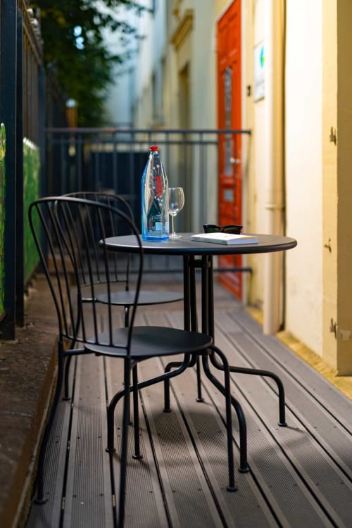 Coin terrasse extérieur de la chambre d'hôtes Un Air De Famille à Vittel avec chaise métallique noire, table ronde, bouteille d'eau et verre