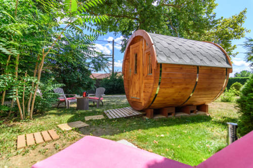 Hébergement insolite extérieur en forme de tonneau avec un lit de 140 X 200 et une grande vitre avec vue sur le jardin