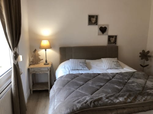 Chambre accueillante du Royal Navy B&B à Dunkerque avec lit gris, lampe, fenêtre et éléments décoratifs muraux.