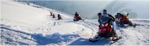 Motoneigistes en course sur les pentes enneigées près d'Hermonville, activités hivernales d'aventure
