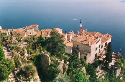 Hôtel De La Fontaine perché sur une falaise surplombant la Méditerranée à Nice, avec toits en terre cuite et drapeau français