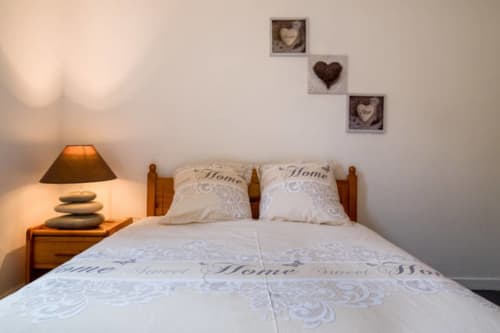 Chambre cosy de style Royal Navy à Dunkerque : lit en bois, literie crème, décoration cœurs et ambiance chaleureuse