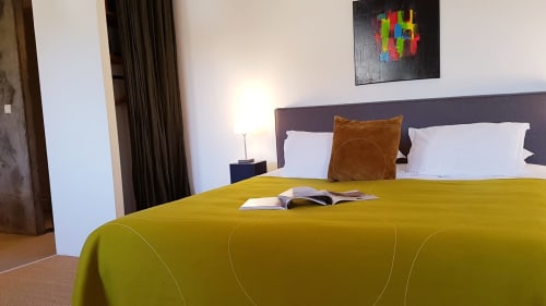 St Andoche-kamer in Moulin Renaudiots in Autun met geel beddensprei, witte kussens, bruine kussen en uitzicht op de tuin
