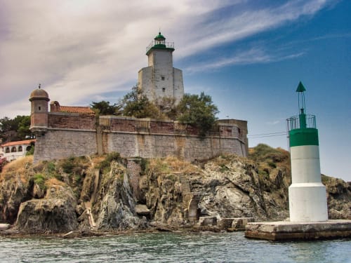 Forteresse côtière historique et phare à Banyuls-sur-Mer, France avec rivage rocheux et eaux turquoise