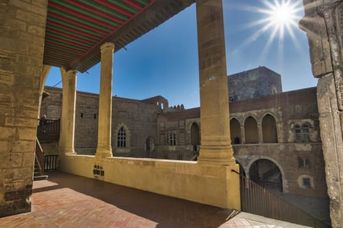 Cour ensoleillée aux colonnes jaunes de la maison d'hôtes de Banyuls-sur-Mer, architecture médiévale en pierre et voûtes