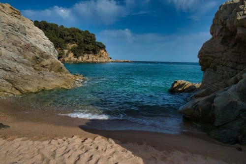 Petite crique isolée aux eaux turquoise et plage de sable fin, encadrée par des falaises rocheuses près de Banyuls-sur-Mer