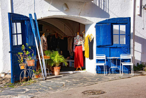 Charmante devanture aux volets bleus et boutique à Banyuls-sur-Mer avec présentoir de vêtements et places assises en terrasse