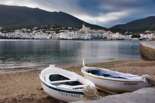 Bateaux de pêche blanchis à la chaux sur la plage de Banyuls-sur-Mer avec le village méditerranéen et les montagnes en arrière-plan