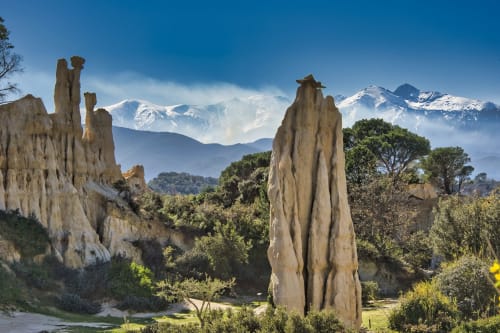 Formations rocheuses spectaculaires près de Banyuls-sur-Mer avec les Pyrénées enneigées et la végétation méditerranéenne en arrière-plan