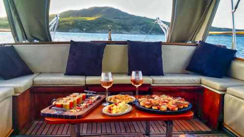 Salon de yacht de luxe à Banyuls-sur-Mer avec mise en bouche, vin et vue sur les montagnes en Méditerranée.
