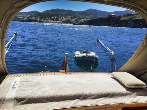 Vue de gîte à Banyuls-sur-Mer : cabine de luxe style bateau, ville côtière méditerranéenne et montagnes.