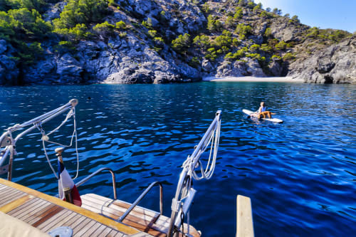 Ponton en bois avec bateaux amarrés surplombant les eaux méditerranéennes cristallines et les falaises rocheuses de Banyuls-sur-Mer