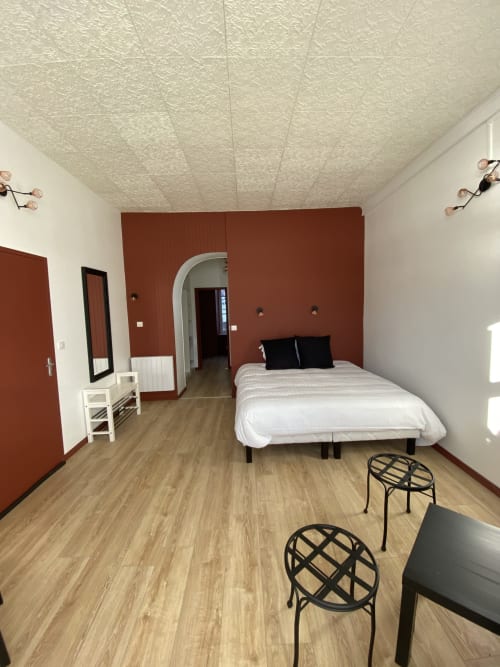 Le lit king-size (180) de la chambre "familiale deluxe" à La bonne hôtesse, ainsi que son coin salon, et le meuble à chaussures.