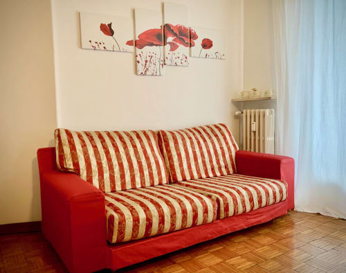 Red sofa in the relaxation area of B&B Ariel, rooms in Verona city center, cozy space for guest relaxation