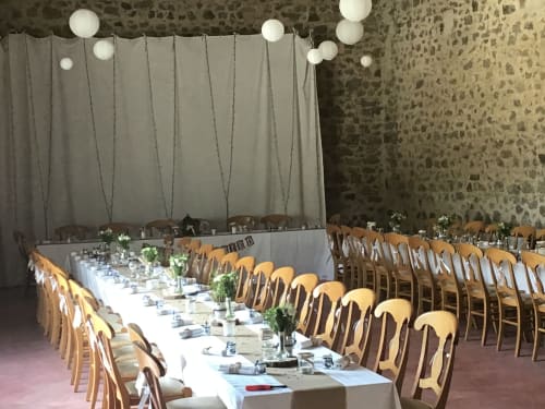 Table de banquet dressée pour un mariage à La Raymondière Gîte en Vernoux-en-Gâtine, France, avec chaises en bois et luminaires suspendus.