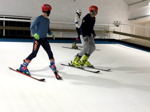 skieurs en salle sur piste synthétique