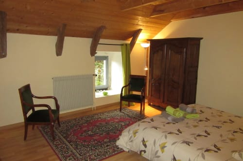 La chambre au nom de la fleur Angélique aux Bastides du Mezenc avec charpente traditionnelle de ferme et plafond bois