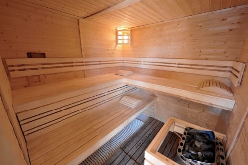 Interior of wooden sauna with benches and heating stove at Espace Ker Gana in Plourin