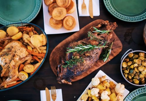 Gourmet dinner spread at Espace Ker Gana featuring roasted meats, potatoes, and vegetables in Plourin