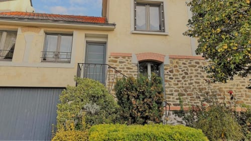 Façade crème de l'hôtel Orval Et Sens à Orvault avec accents de pierre, murs couverts de lierre et verdure soignée