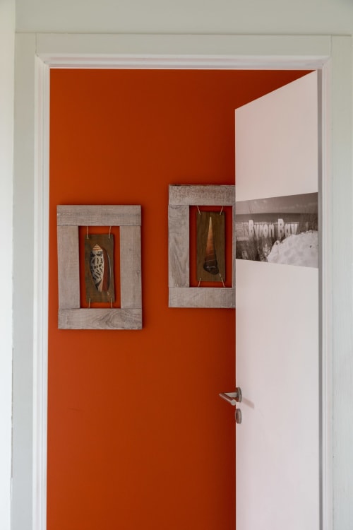 Chambre Byron Bay à l'hôtel Côte Et Dune à Biscarrosse Plage avec un mur d'accent orange vibrant et des œuvres d'art encadrées en bois