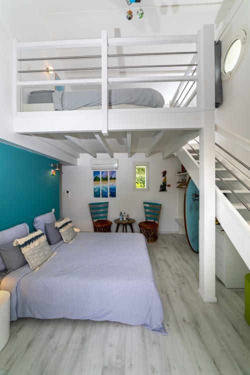 Chambre moderne avec mur d'accent bleu-vert, lit mezzanine et chaises rayées à Côte et Dune Biscarrosse Plage