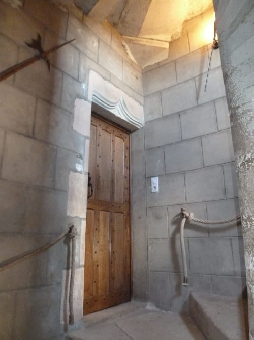 Pasillo de piedra con puerta de madera en el Château De Clusors, una casa rural francesa en Saint-Menoux