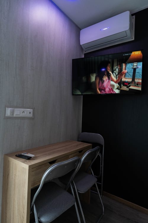 Habitació triple moderna a l'Hôtel Rocade Pamiers amb escriptori, cadira, televisor de pantalla plana mural i aire condicionat split il·luminat en porpra