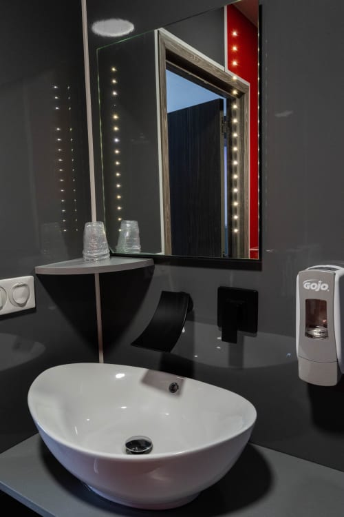 Bany modern a l'Hôtel Rocade a Pamiers amb lavabo blanc, mirall il·luminat i accessoris negres epurats