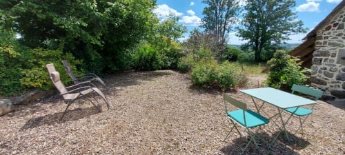 Terrasse de jardin privé du cottage Le Mas De Rigoulac avec chaises longues, table à manger et vue sur la campagne