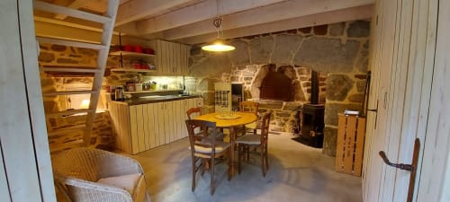 Intérieur du gîte Le Mas De Rigoulac avec cheminée en pierre, salle à manger et kitchenette à Argences-en-Aubrac