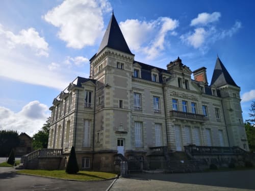 Hôtel Orval Et Sens de style château à Orvault, France avec tourelles et façade en pierre sous un ciel bleu