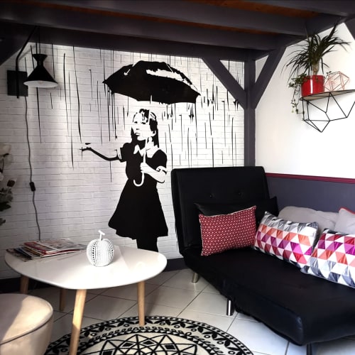 Chambre moderne à l'Orval Et Sens avec fresque murale de style Banksy, canapé noir et table d'appoint blanche à Orvault