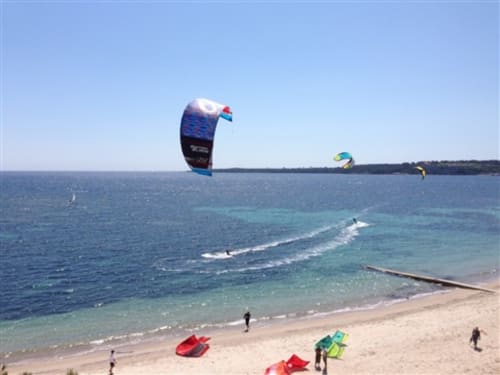 Kitesurfer und Surfer am Strand von Cannes mit bunten Drachen über türkisfarbenem Wasser