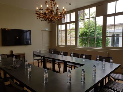Salle de conférence moderne aux Cabines d'Houlgate avec table spacieuse, carafes d'eau et lustre élégant