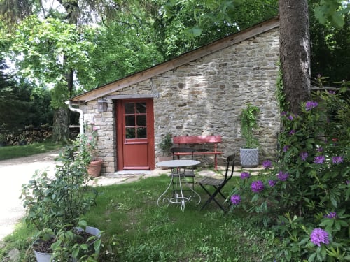 Le cottage La Bergerie au Petit Manoir de Kériolet à Concarneau avec façade en pierre, porte rouge et coin de détente dans le jardin