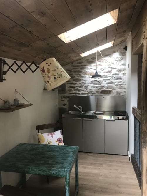 Petite cuisinette chaleureuse au Petit Manoir de Kériolet, Concarneau avec murs en pierre, puits de lumière et table verte